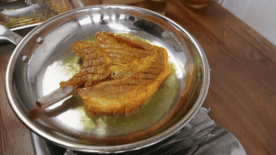 A Piece Of Meat Is Being Cooked In A Pan On A Stove GIF