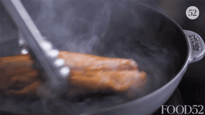 A Piece Of Meat Is Being Cooked In A Pan With The Number 52 On It GIF