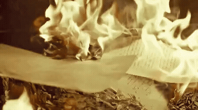 A Piece Of Paper Is Burning In A Pile Of Papers . GIF