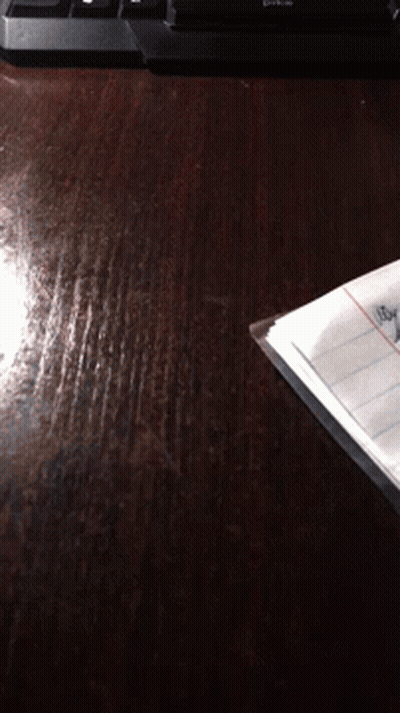 A Piece Of Paper Is Laying On A Wooden Table Next To A Keyboard That Says Dtkc GIF