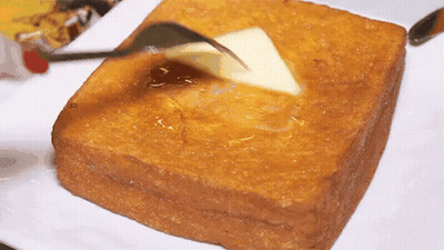A Piece Of Toast Is Being Buttered With A Fork . GIF