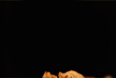 A Pile Of Fried Chicken Wings On A Black Table GIF