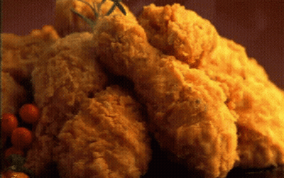 A Pile Of Fried Chicken With Tomatoes And Rosemary On A Table GIF
