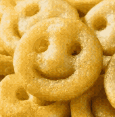 A Pile Of Fried Potatoes With Smiley Faces On Them GIF