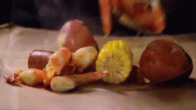 A Pile Of Shrimp , Corn , Potatoes , Onions And Other Vegetables On A Table . GIF