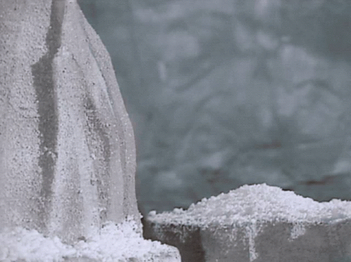A Pile Of Snow Is Sitting Next To A Rock GIF