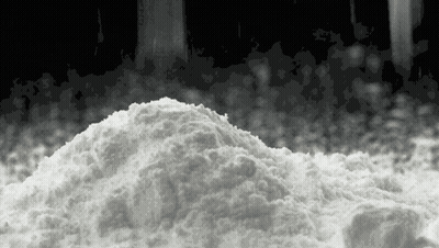 A Pile Of White Powder Is Sitting On A Black Surface . GIF