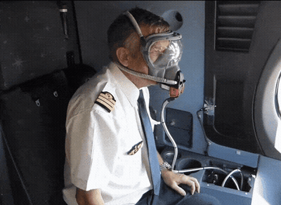 A Pilot Is Wearing A Gas Mask And Goggles While Sitting On An Airplane GIF