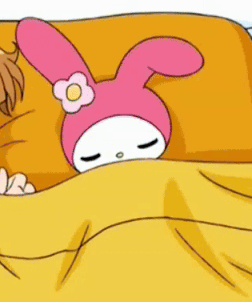 A Pink Bunny With A Flower On Its Head Is Laying On A Bed With A Yellow Blanket . GIF