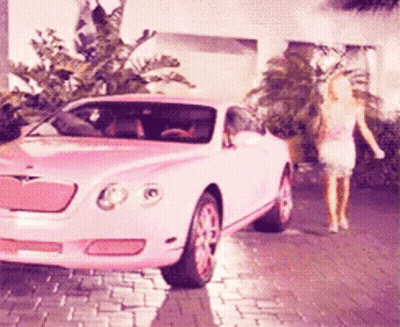 A Pink Car Is Parked On A Brick Driveway GIF