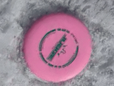 A Pink Frisbee With A Green Circle Around It Is Laying In The Snow GIF