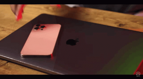 A Pink Iphone Is Sitting On Top Of An Apple Laptop GIF