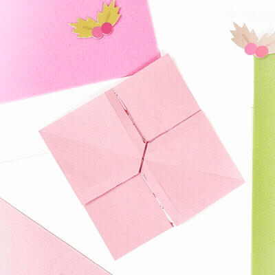 A Pink Origami Bird With Leaves On It Is Sitting On A Table GIF