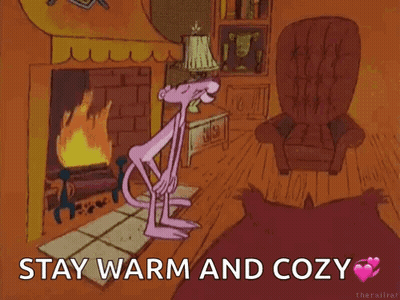 A Pink Panther Is Standing In Front Of A Fireplace With The Words " Stay Warm And Cozy " Above Her GIF