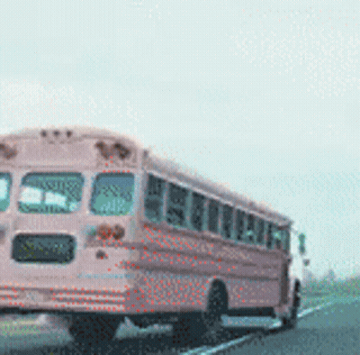 A Pink School Bus Drives Down A Highway GIF
