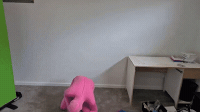 A Pink Stuffed Animal Sits In Front Of A Desk In An Empty Room GIF