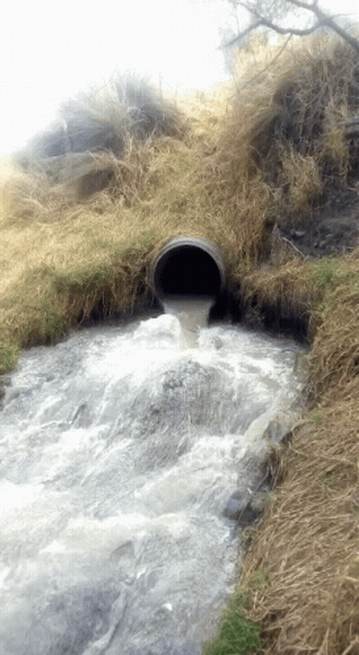 A Pipe With Water Coming Out Of It In A Field GIF