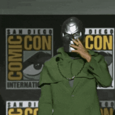 A Pixel Art Drawing Of A Person Standing In Front Of A Comic Con Sign GIF