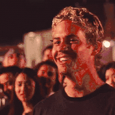 A Pixelated Image Of A Man Smiling In Front Of A Crowd Of People GIF