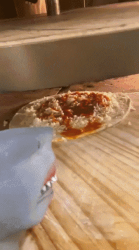 A Pizza Is Being Cooked On A Wooden Cutting Board GIF