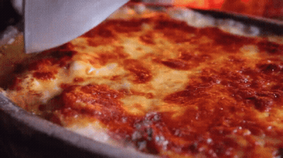 A Pizza With A Lot Of Cheese And Sauce Is Being Scooped Out Of A Pan With A Spatula . GIF