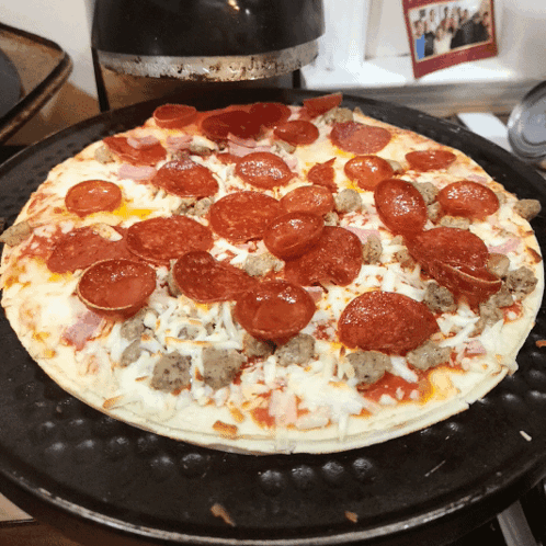 A Pizza With Pepperoni Ham And Sausage On Top Of It GIF