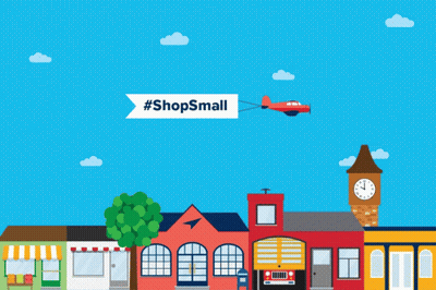 A Plane Is Flying Over A Small Town With A Banner That Says #Shopssmall GIF