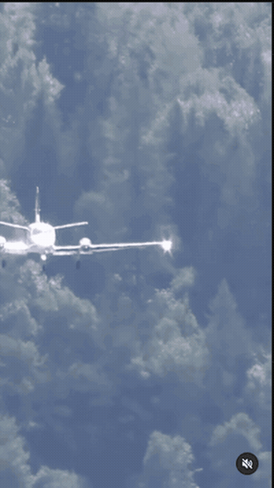 A Plane Is Taking Off From A Grassy Runway With A Watermark That Says ' Zz ' On The Bottom Right GIF