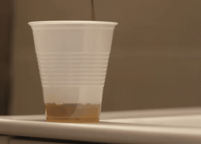 A Plastic Cup Filled With Brown Liquid Sits On A Counter GIF