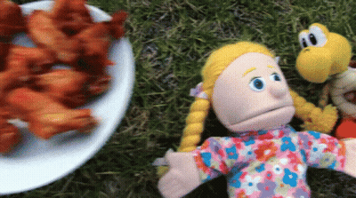 A Plate Of Chicken Wings Sits Next To A Puppet GIF