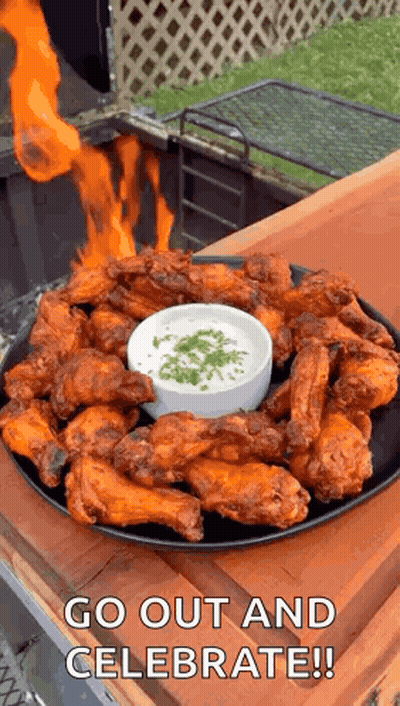 A Plate Of Chicken Wings With A Dipping Sauce And Fire Coming Out Of Them . GIF