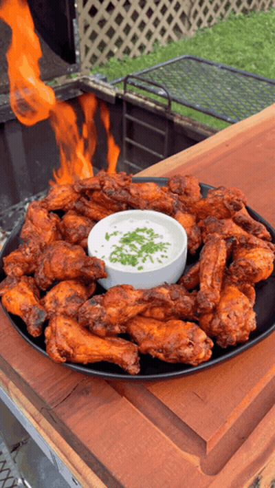 A Plate Of Chicken Wings With A Dipping Sauce On A Wooden Table GIF
