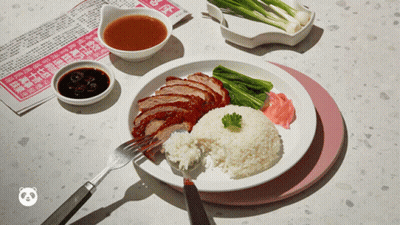 A Plate Of Food With Rice And Meat On A Table With A Newspaper In The Background GIF