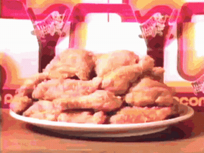A Plate Of Fried Chicken Sits On A Table In Front Of A Wendy 'S Sign GIF