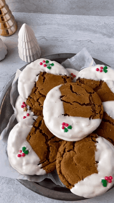 A Plate Of Gingerbread Cookies With White Frosting And Holly On Them GIF