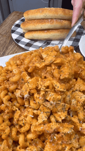 A Plate Of Macaroni And Cheese With Garlic Bread On A Table GIF