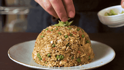 A Plate Of Rice With Vegetables And Sesame Seeds On It GIF