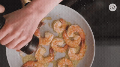 A Plate Of Shrimp Is Being Sprinkled With Salt And Pepper GIF