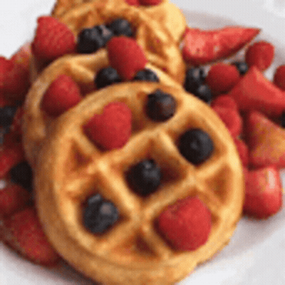 A Plate Of Waffles With Strawberries And Blueberries On It . GIF