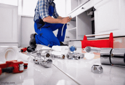 A Plumber Is Kneeling On The Floor Working On A Sink GIF
