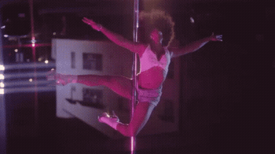 A Pole Dancer In A Pink Outfit Is Dancing In The Dark GIF