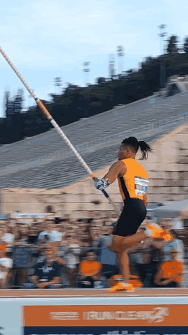 A Pole Vaulter Is Jumping In Front Of A Sign That Says Runner GIF