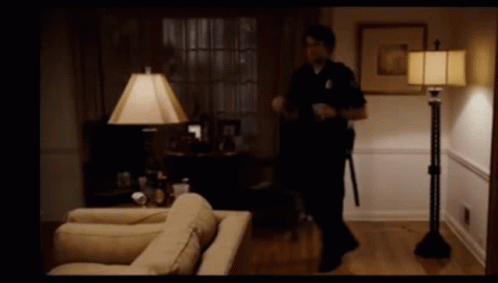 A Police Officer In A Living Room With A Lamp GIF