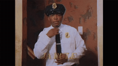 A Police Officer Is Adjusting His Tie In Front Of A Wall That Says Ja Rule GIF