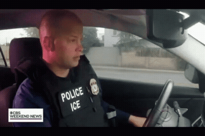 A Police Officer Is Driving A Car With Cbs Weekend News Written On The Bottom GIF