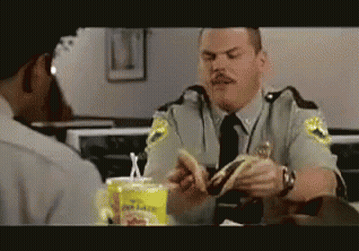 A Police Officer Is Eating A Hamburger In A Restaurant GIF