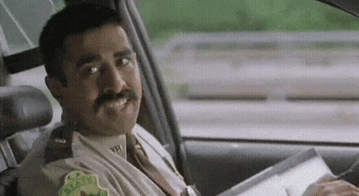 A Police Officer Is Sitting In The Driver 'S Seat Of A Car Holding A Piece Of Paper . GIF