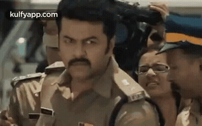 A Police Officer Is Standing In Front Of A Crowd Of People . GIF