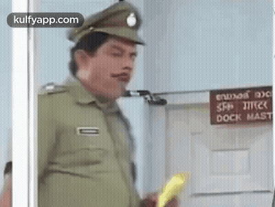 A Police Officer Is Standing In Front Of A Door Holding A Yellow Object . GIF