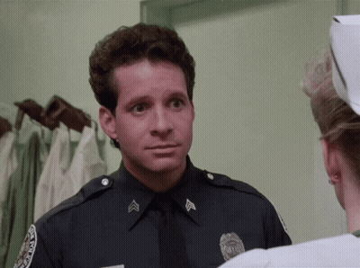 A Police Officer Is Talking To A Nurse Who Is Wearing A White Cap GIF